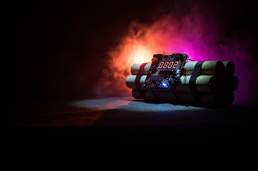 Image of a time bomb against dark background. Timer counting down to detonation illuminated in a shaft light shining through the darkness, conceptual image