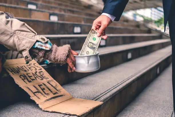 Photo of Businessman giving donation dollar cash with sleeping homeless person