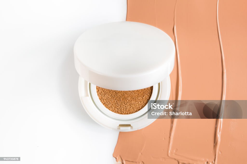 Foundation cushion on white background. Foundation cushion on half of the surface of a tonal base, smeared on a white background Make-Up Stock Photo