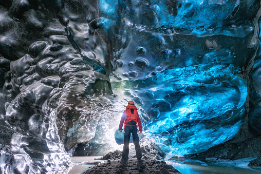 Ice Cave in Vatnajokull, Iceland.Male tourists watch the beauty of the caves filled with blue ice.