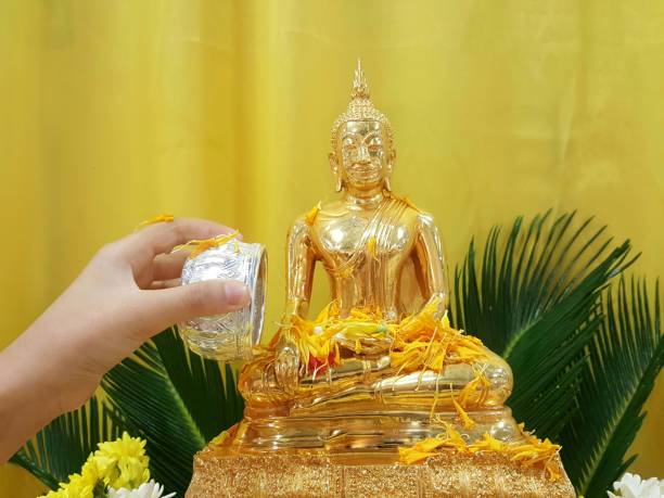 istock Hand hold silver bowl for pour water onto Buddish  statue 943754906