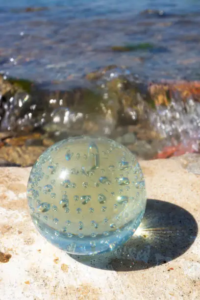 Sun reflecting in a glass ball on the beach.Crystal ball at the beach