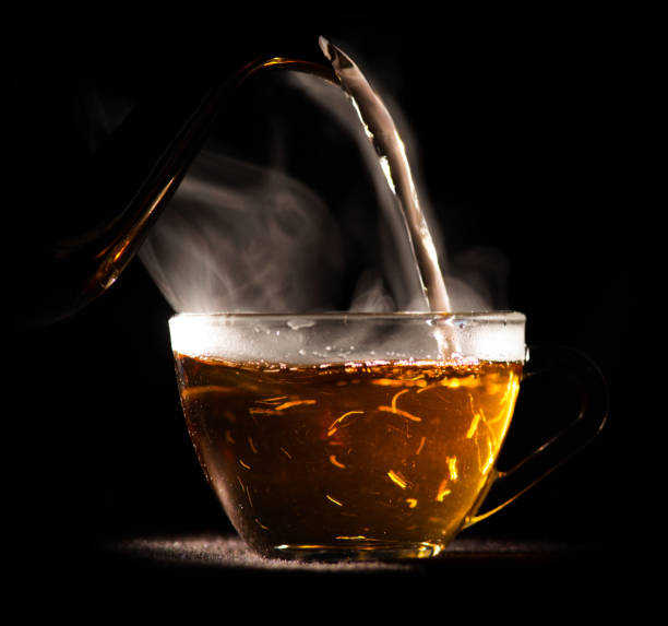 istock hot tea is poured from pot into glass mug 943762290