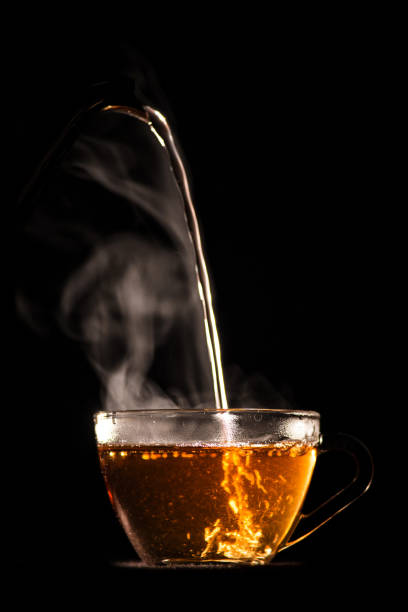 istock hot tea is poured from pot into glass mug 943762296