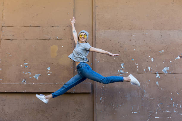 joven saltando delante de pared - funky people cool women fotografías e imágenes de stock