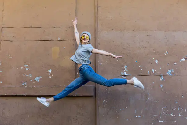 Young woman jumping front of wall