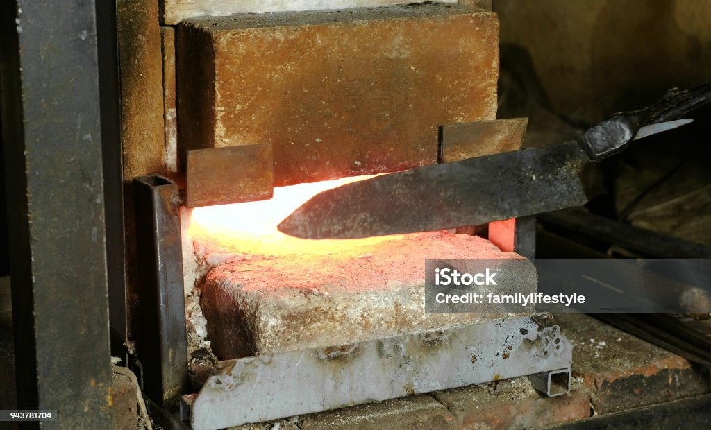 Making the knife out of metal at the forge. Heating of metal billets in the furnace. Making the knife out of metal at the forge. Heating of metal billets in the furnace Barracks Stock Photo