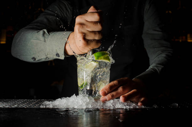 Bartender squeezing juice from fresh lime using citrus press and splashing it out Bartender squeezing juice from fresh lime in a glass using citrus press and splashing it out making an alcoholic cocktail tequila drink photos stock pictures, royalty-free photos & images
