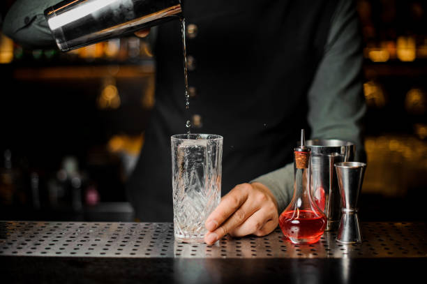 istock Barman puring a fresh alcoholic drink from shakerinto a glass 943801126
