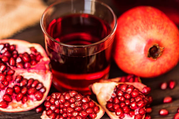 istock Ripe pomegranates with glass of juice on table 943803908