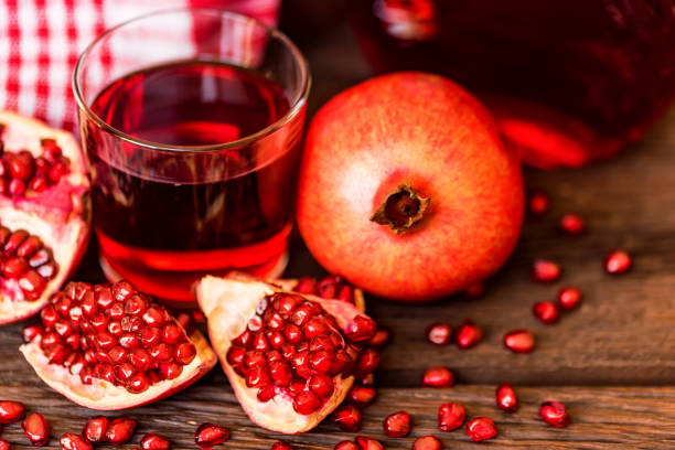 istock Ripe pomegranates with glass of juice on table 943803962