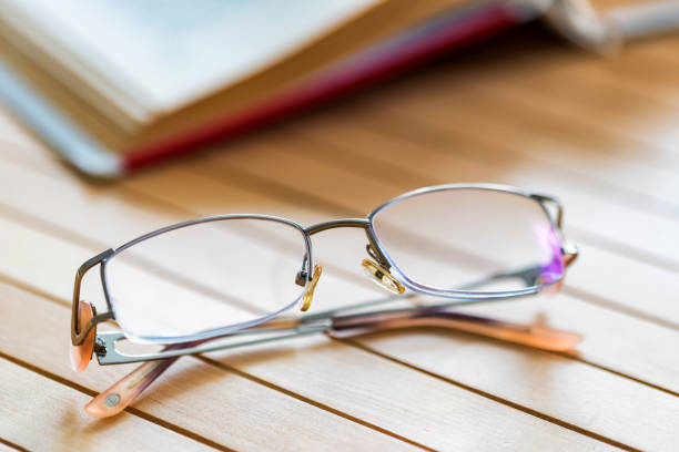 istock Open book and glasses on wooden table close 943804320