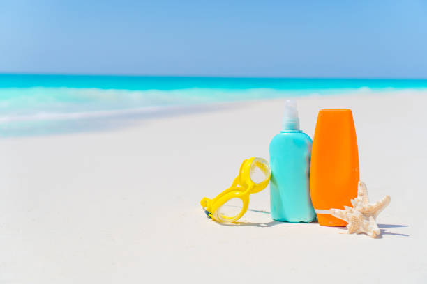 istock Suncream bottles, glasses, starfish on white sand beach 943818382