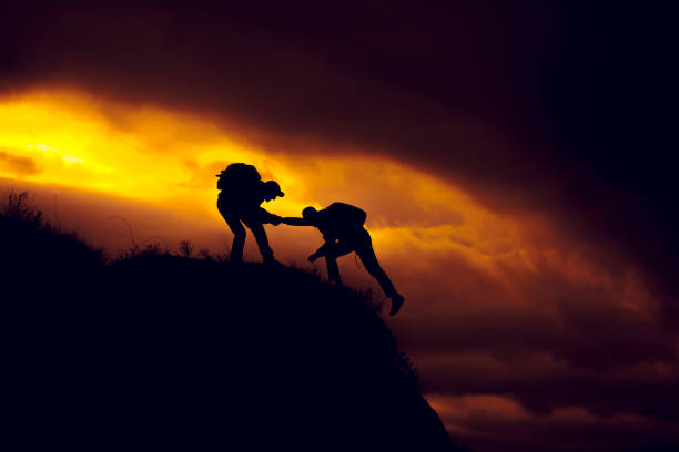 istock Silhouette of helping hand between two climber 943818960