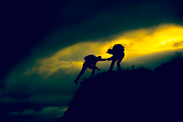 istock Silhouette of helping hand between two climber 943818978