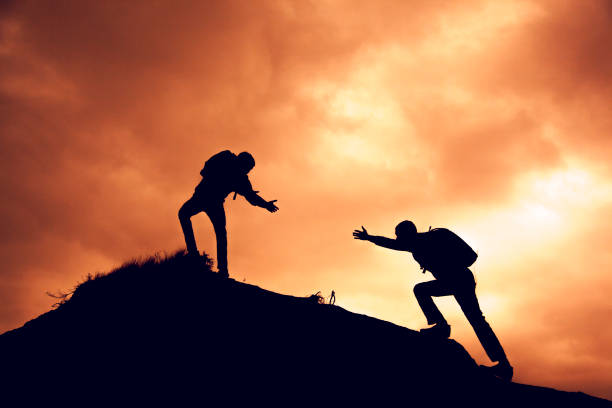 istock two people  help each other on top of a mountain climbing team 943818984