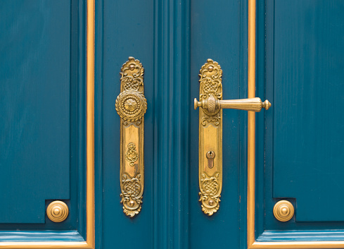 antique ornate gold door handle closeup on blue wooden door