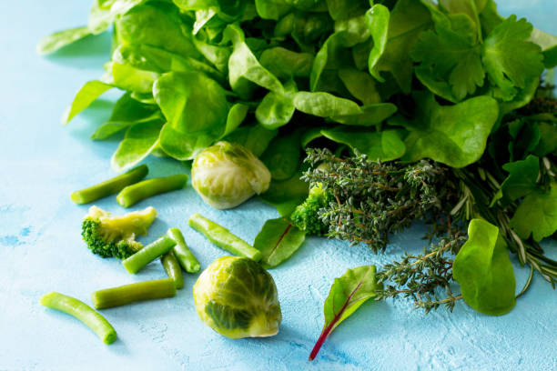 Food background. Various summer green vegetables, spices and fresh herbs on blue concrete background. Diet, concept of vegetarian food.
