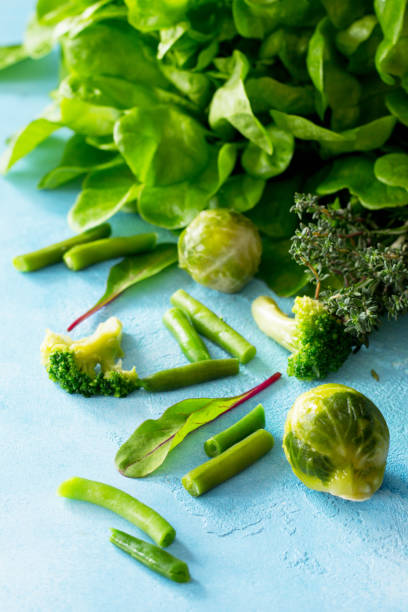 Food background. Various summer green vegetables, spices and fresh herbs on blue concrete background. Diet, concept of vegetarian food.