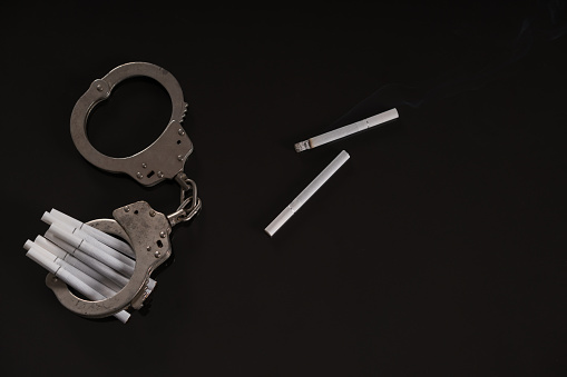 Cigarette with handcuff on black background