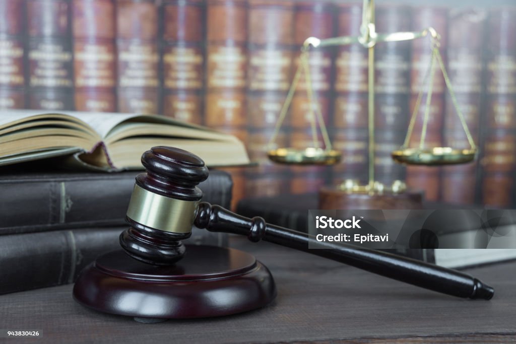 Allegory of  justice Wood gavel, soundblock, scales and open old book against the background of a row of antique books bound in leather Legal System Stock Photo