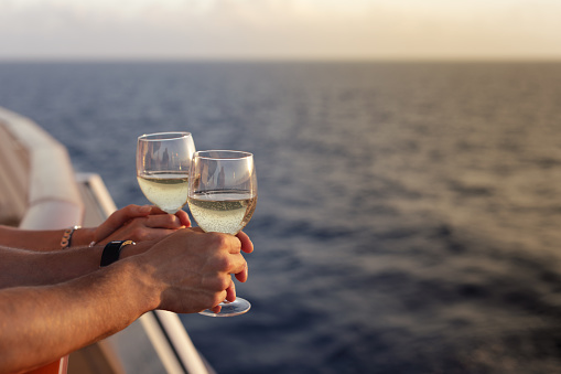 Handsome man and beautiful woman standing with glasses white wine on cruise ship in caribbean sea