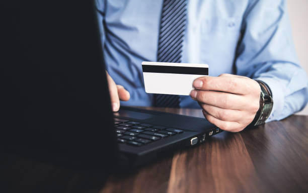 istock Man using laptop and showing credit card. 943831660