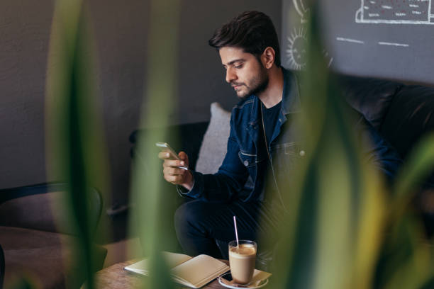 istock Young man using smart phone in coffee shop 943834868