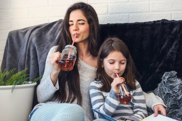 девушки пьют сок весело вместе дома - sibling sweden family smiling стоковые фото и изображения