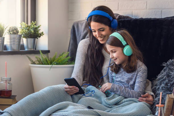 mother and daughter having fun with smart phone and headphones - parent mother music listening imagens e fotografias de stock