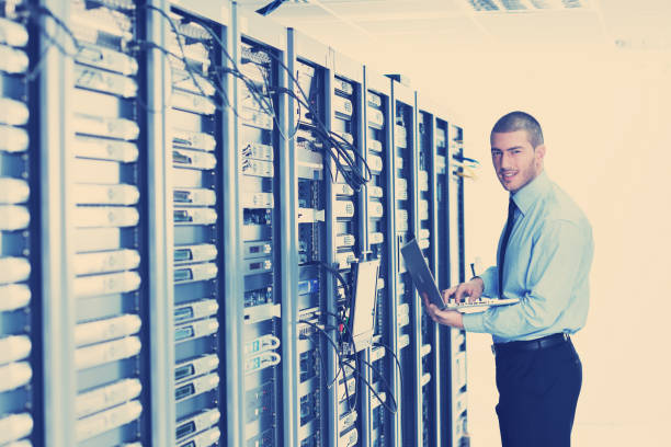 istock businessman with laptop in network server room 943841708