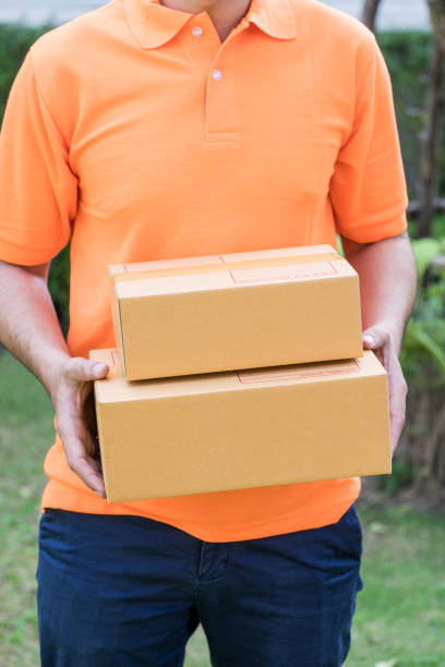 istock Delivery man in orange is handing packages 943841938