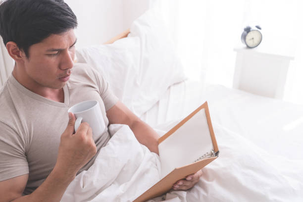 istock Asian male is studying and drink coffee on morning bed 943842270