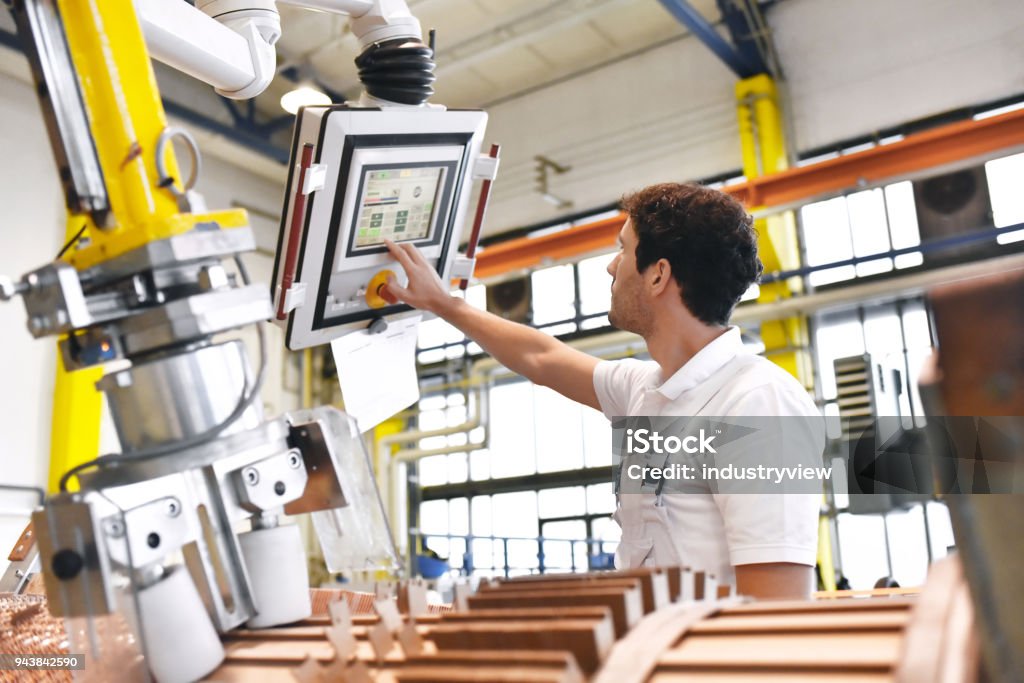 los trabajadores jóvenes mecánica operan una máquina para enrollar alambre de cobre - fabricación de transformadores en una fábrica de - Foto de stock de Industria libre de derechos