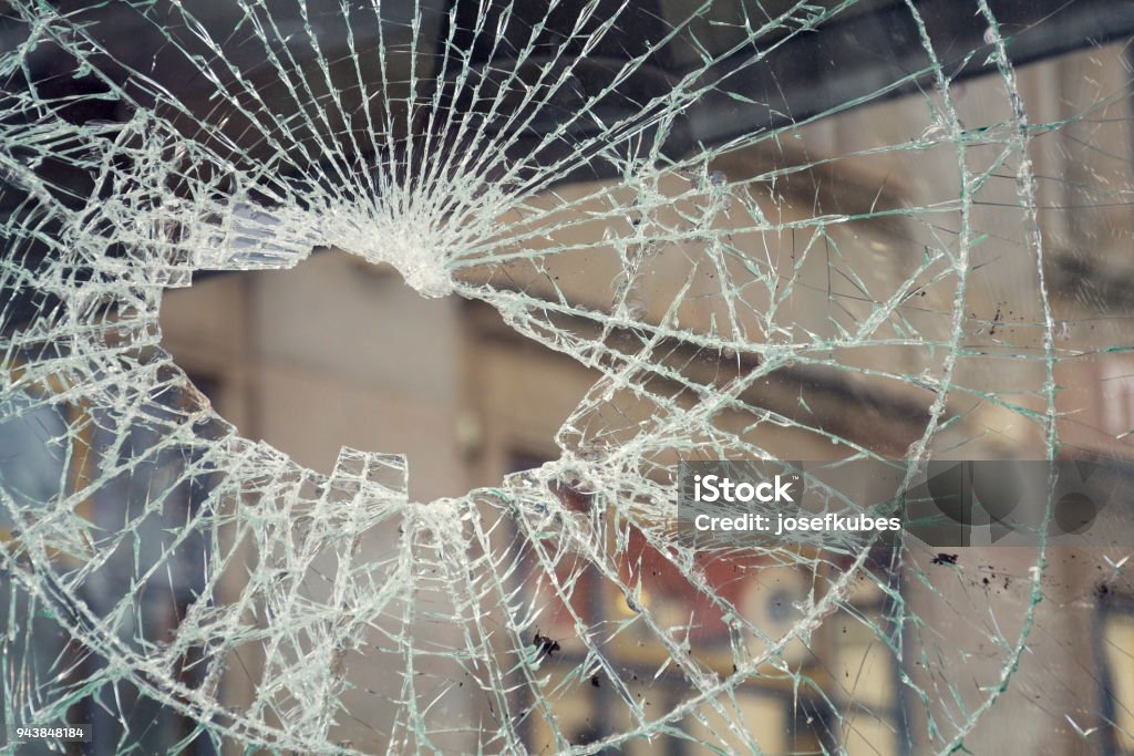 Hole in broken shattered security glass, insurance security crime concept Hole in broken shattered security glass, insurance, security, vandalism or crime concept Vandalism Stock Photo
