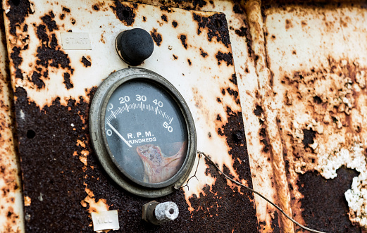 RPM gauge on an old rusty panel with chipping peeling paint flaking away to the ground