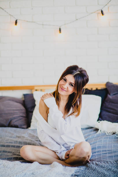 istock Young slender brunette sitting on a big bed 943856972