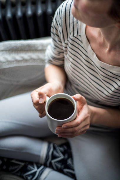 istock Young woman enjoying coffee and relaxing on a sofa 943859908