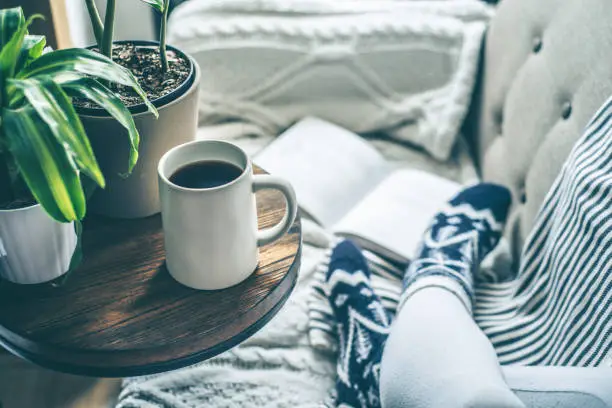 Photo of Young woman enjoying coffee and relaxing on a sofa with a book