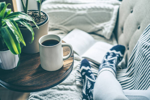 młoda kobieta delektując się kawą i relaksując się na kanapie z książką - book reading white women zdjęcia i obrazy z banku zdjęć