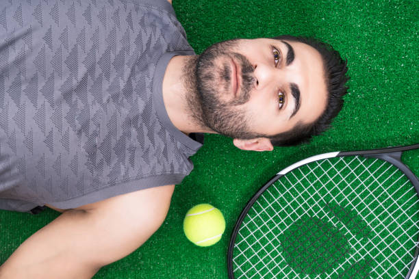 istock Tennis male player lying down on the grass contemplating 943866480