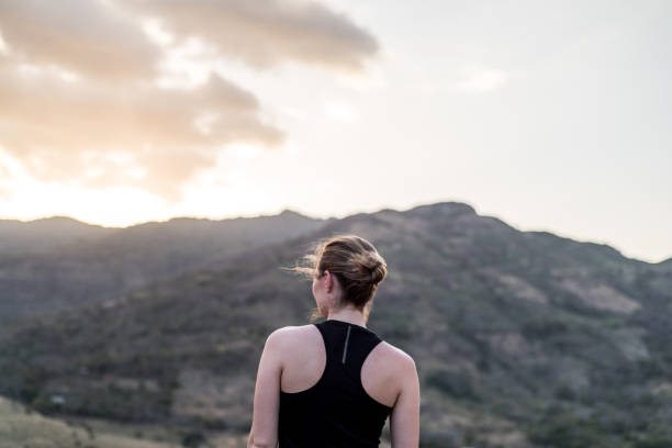istock Young Woman Looking out over a beautiful landscape at sunset 943869876