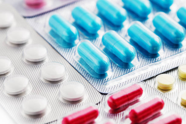 mucchio di pillole mediche in bianco, blu e altri colori. pillole in confezione di plastica. concetto di assistenza sanitaria e medicina. - pill foto e immagini stock