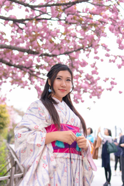 istock Young woman kimono standing under cherry tree 943881928