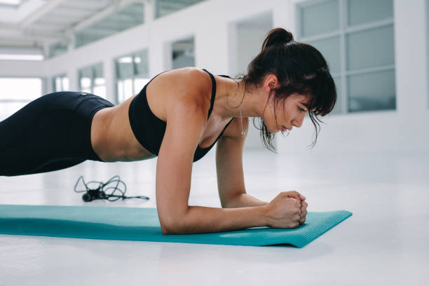 istock Muscular young woman doing planks exercise 943885220