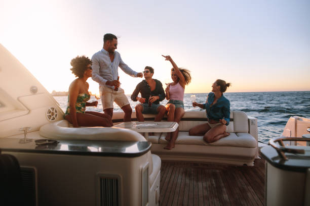 Group of friends enjoying in a boat party Group of happy friends having a boat party. Diverse men and women having drinks at sunset yacht party and dancing. drinks on the deck stock pictures, royalty-free photos & images