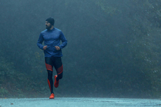 istock Motivated young man running in the rain 943894178