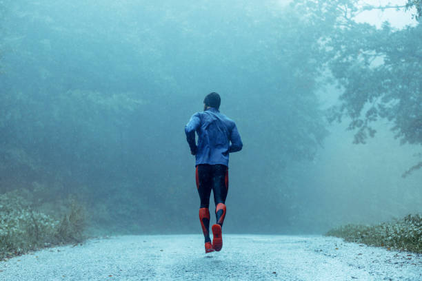 istock Motivated young man running in the rain 943894262