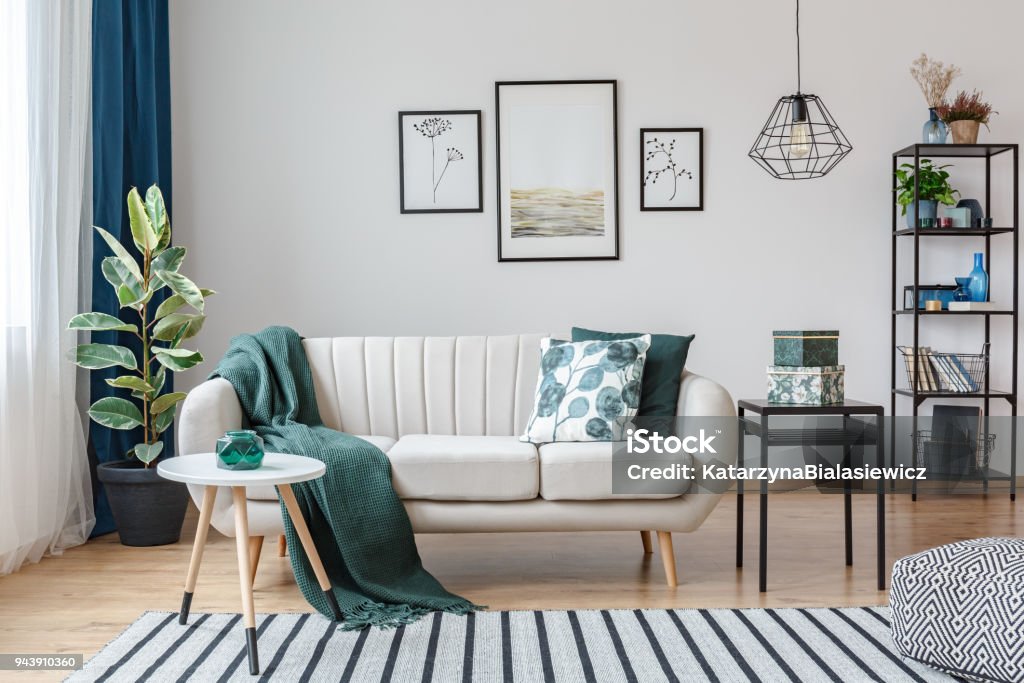 Posters in cozy apartment interior Black table next to sofa with green blanket in cozy apartment interior with gallery of posters Living Room Stock Photo