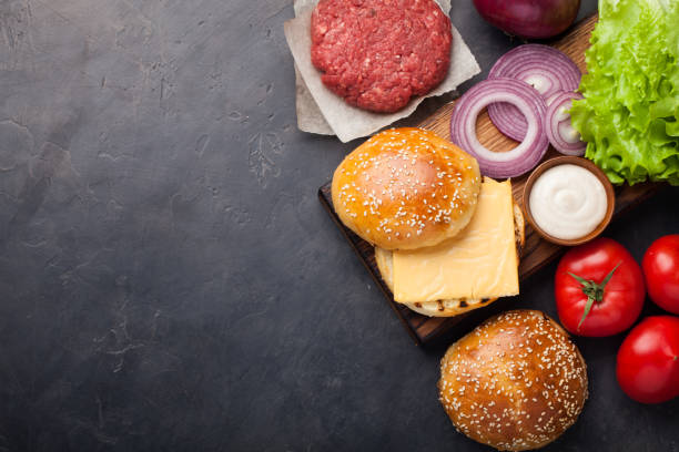 istock Hamburger Building Kit. Fresh ingredients for Burger on dark stone table. Top view with copy space 943910546